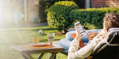Mann im Garten nutzt die DHL & Paket App auf seinem Handy